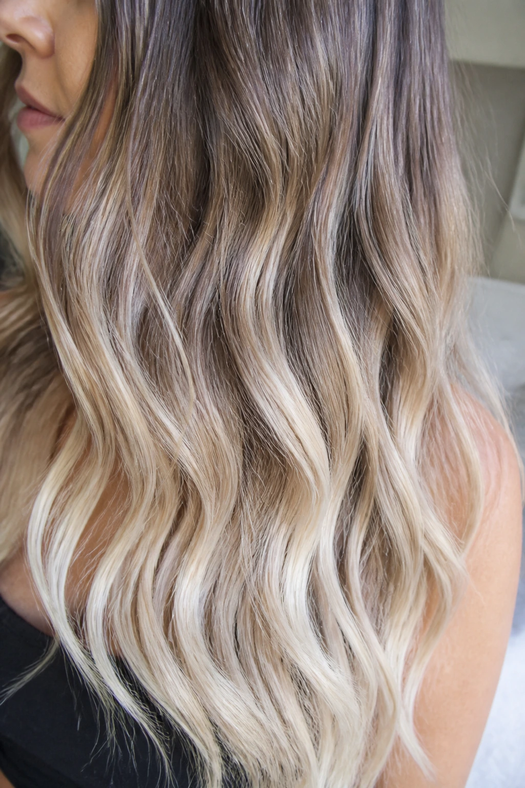 Close-up of a real woman's hair with icy beige ends and root shadow on waves