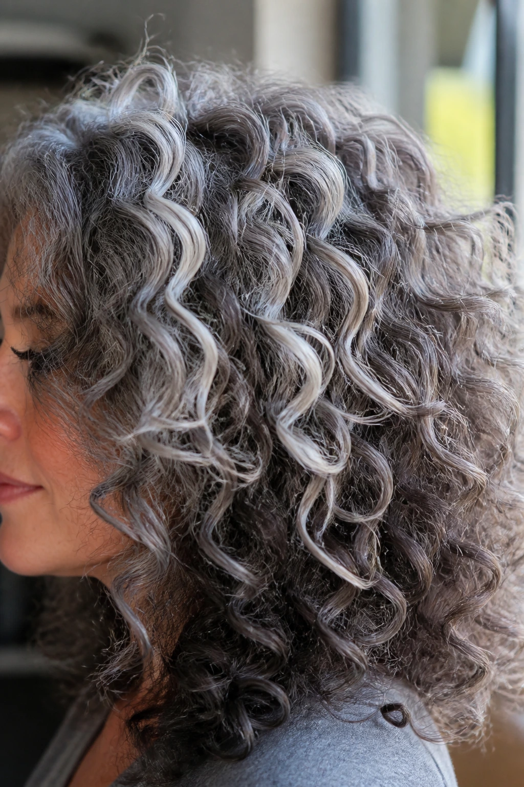 Close-up of curly gray hair showing layered shade variation.