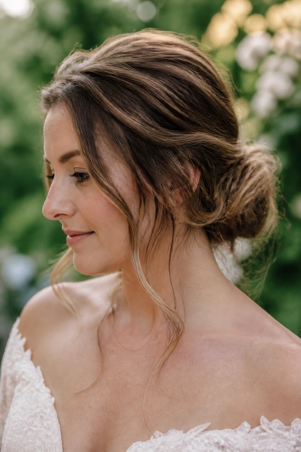 Close-up of bride with a loose garden bun and face-framing pieces in a garden setting