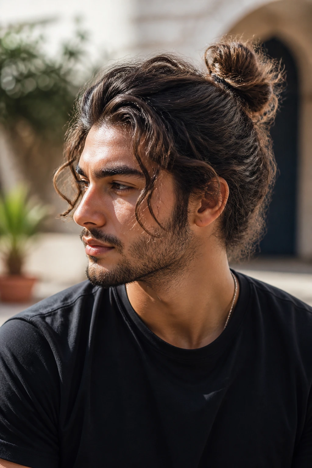 Portrait of a man with loose man bun and face-framing waves.