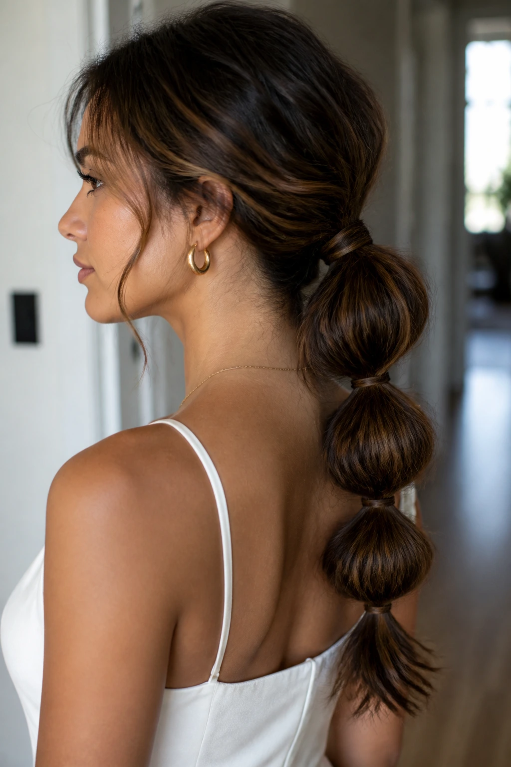 Profile of a real woman showing a low bubble ponytail with evenly spaced bubbles