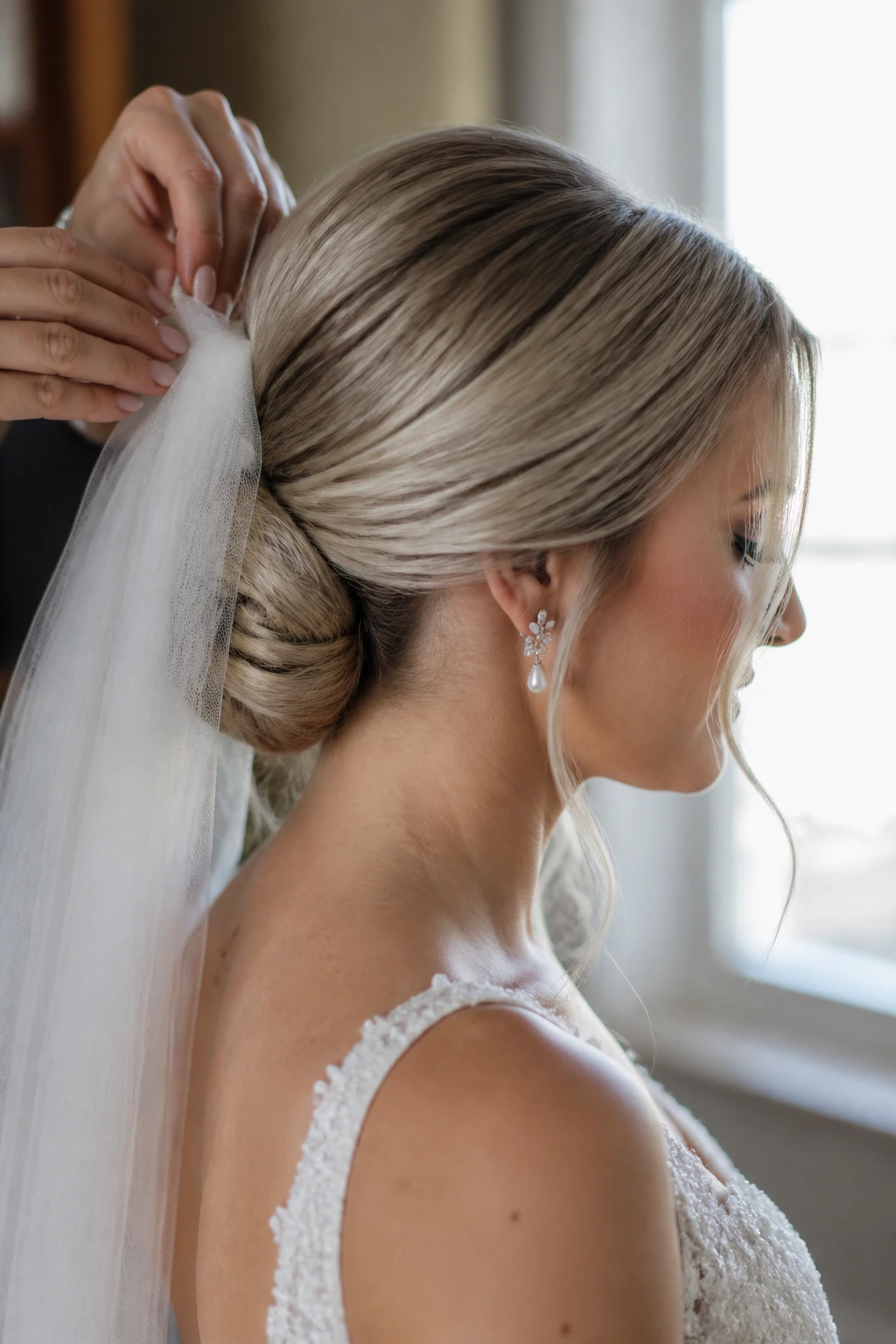 Close-up of a bride's low bun at the nape with veil anchor