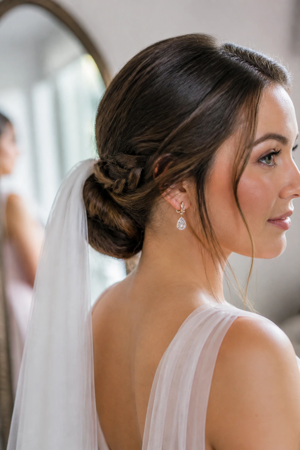 Close-up of a real woman with a low bun and braided veil path in a bridal dressing room