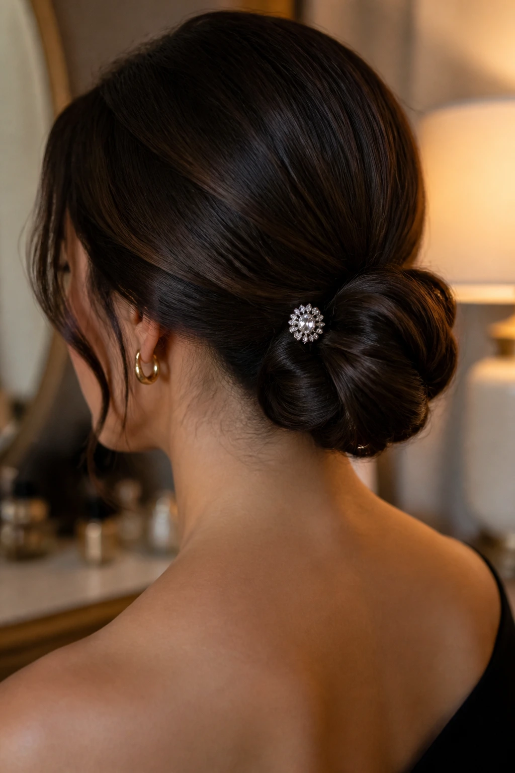 Close-up of a real woman's nape with a low knot and jewel pin.