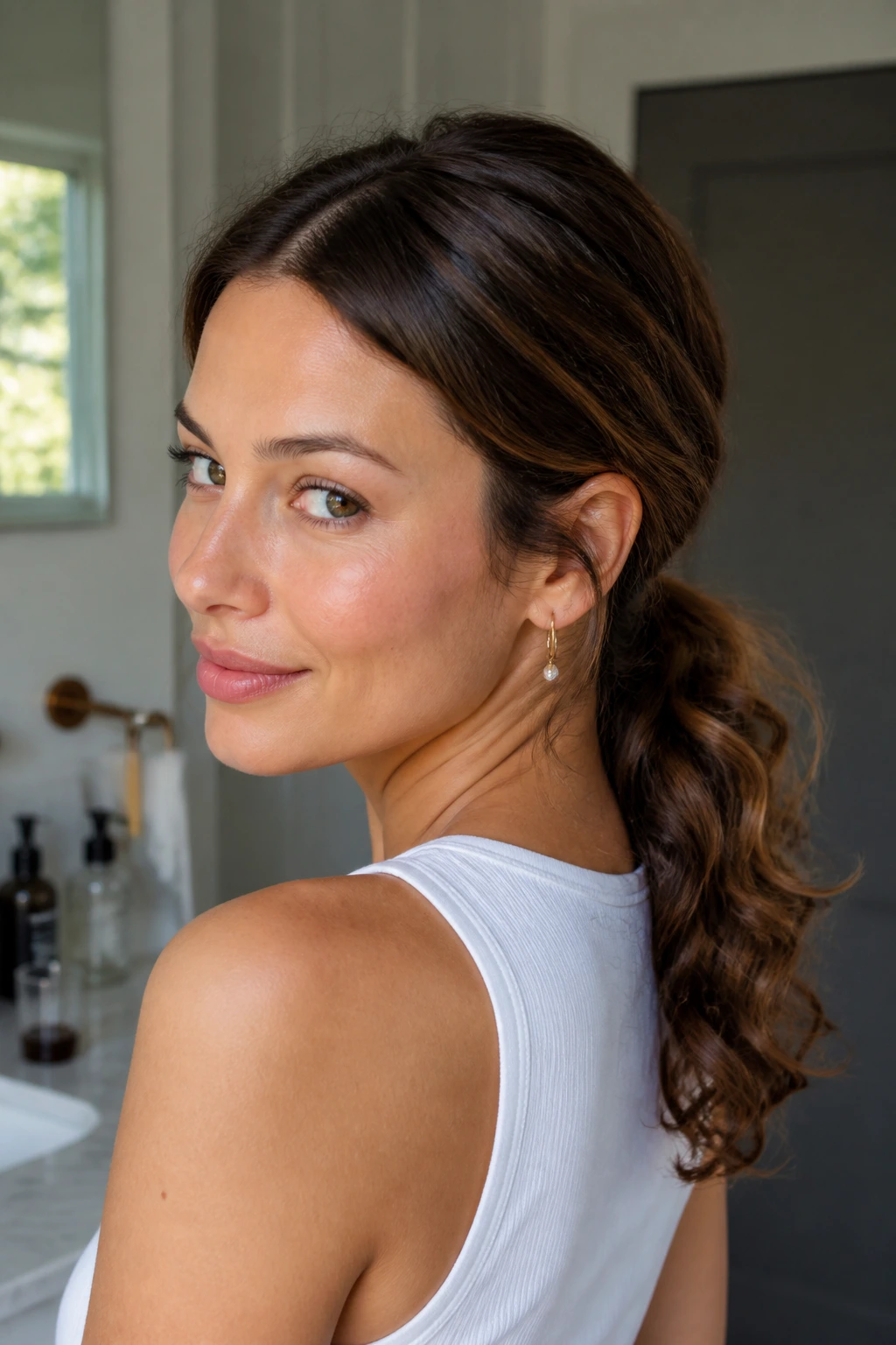 Real woman with a low textured ponytail at the nape showing root texture.