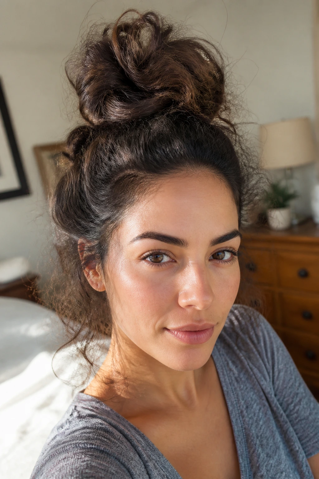 Close-up of a real woman with thick frizzy hair in a loose high top knot
