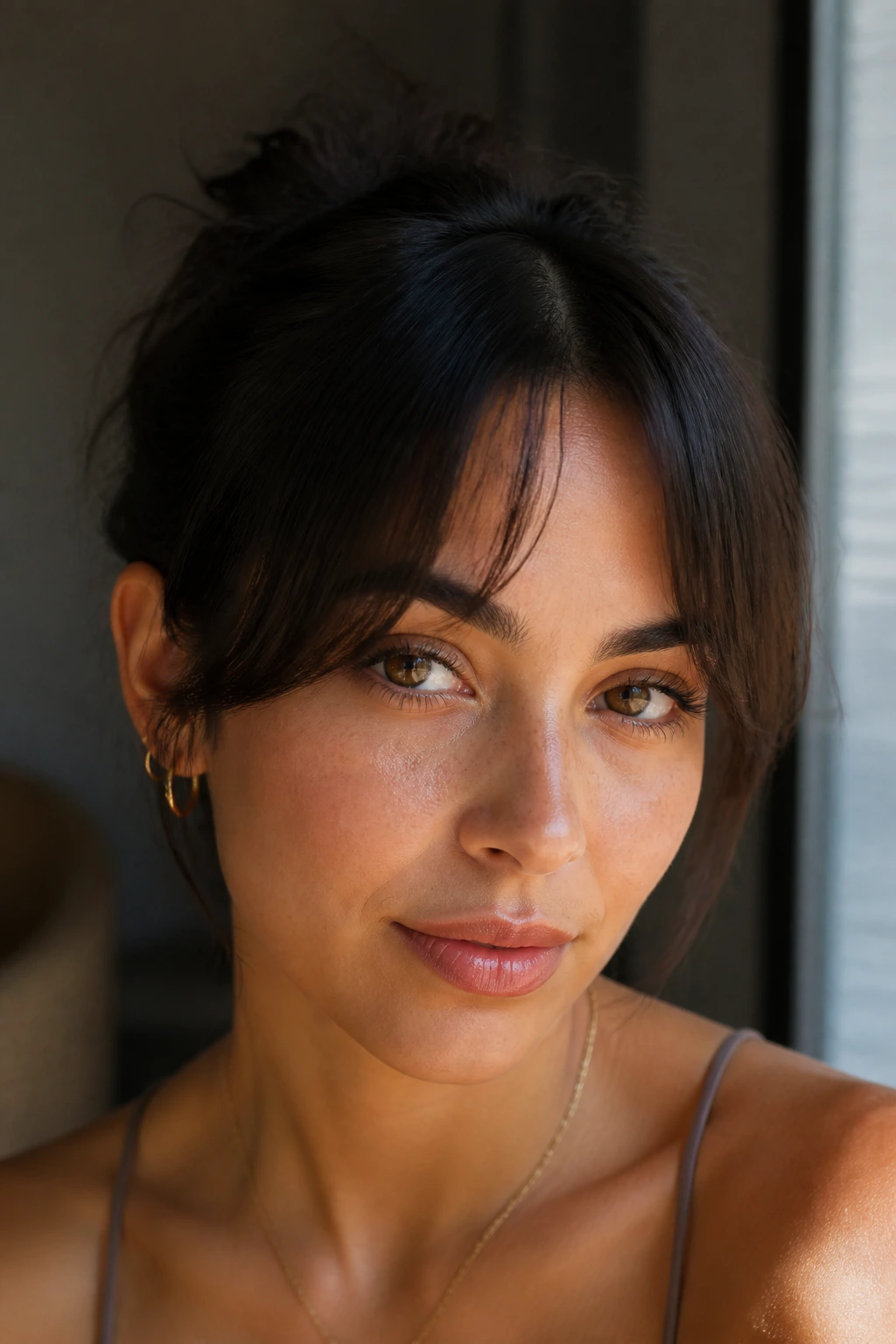 Person with minimalist center fringe near the brow in warm window light.