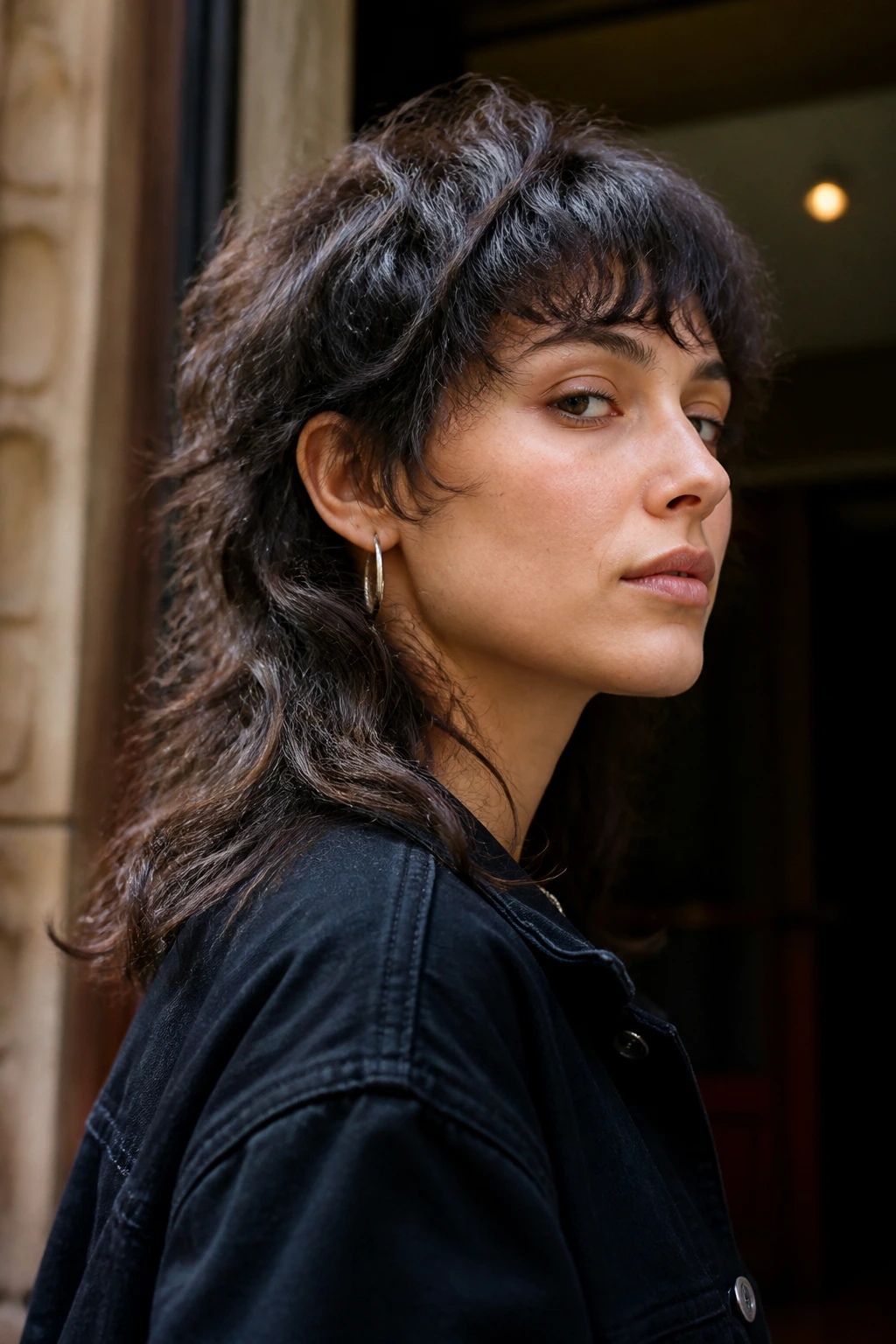 Real person wearing a bold mullet-forward wolf hairstyle in a side-profile shot.
