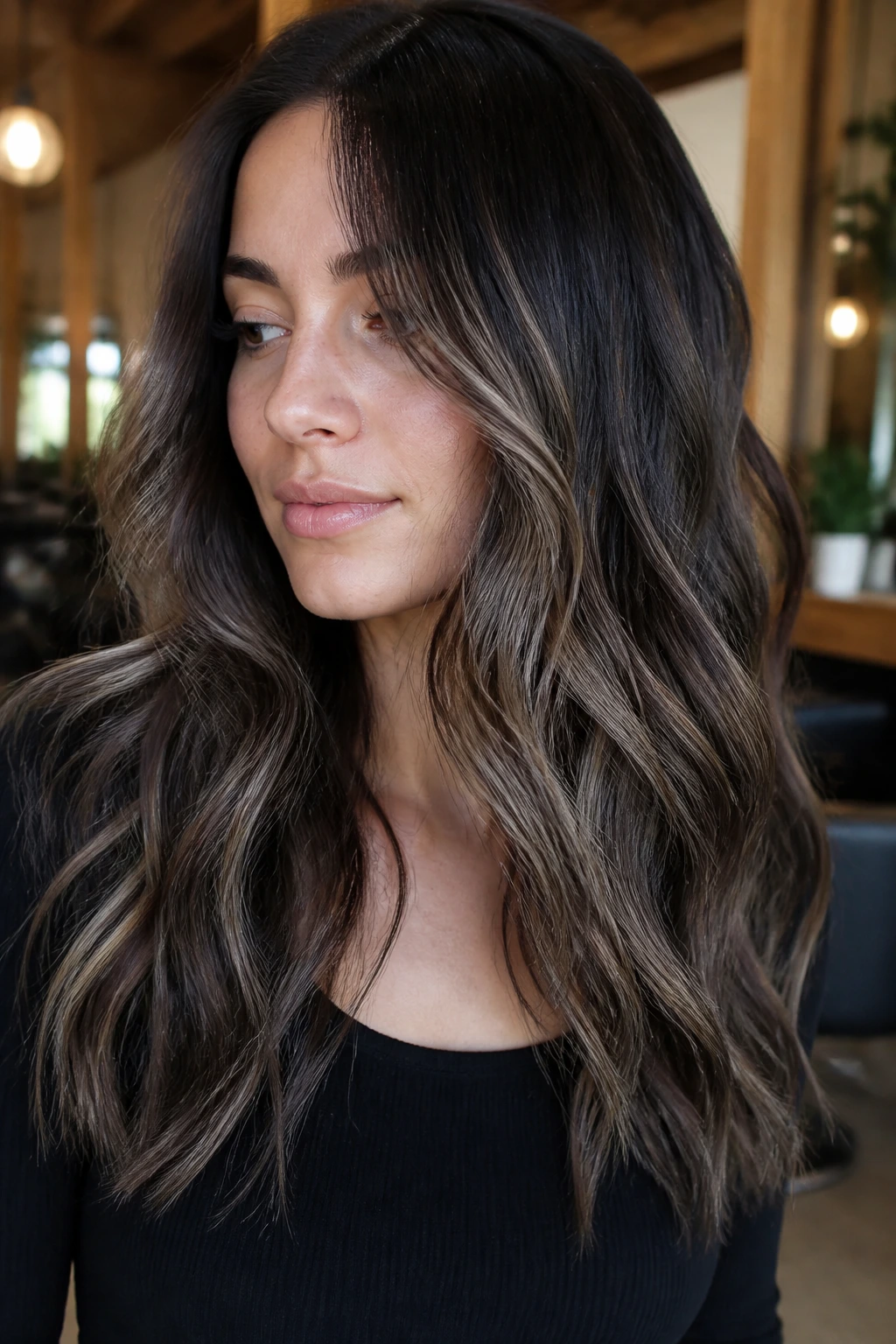 Close-up of a real woman with mushroom bronde balayage on dark base and smoky beige ribbons.