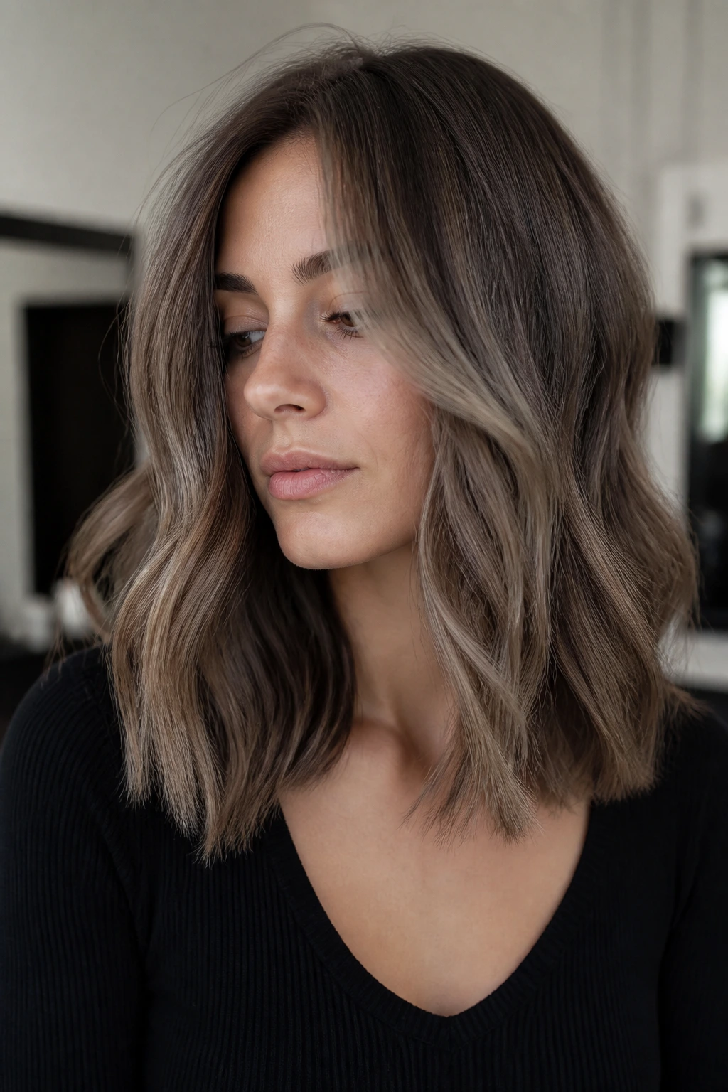 Real woman with mushroom brown balayage on medium-length hair, cool indoor lighting
