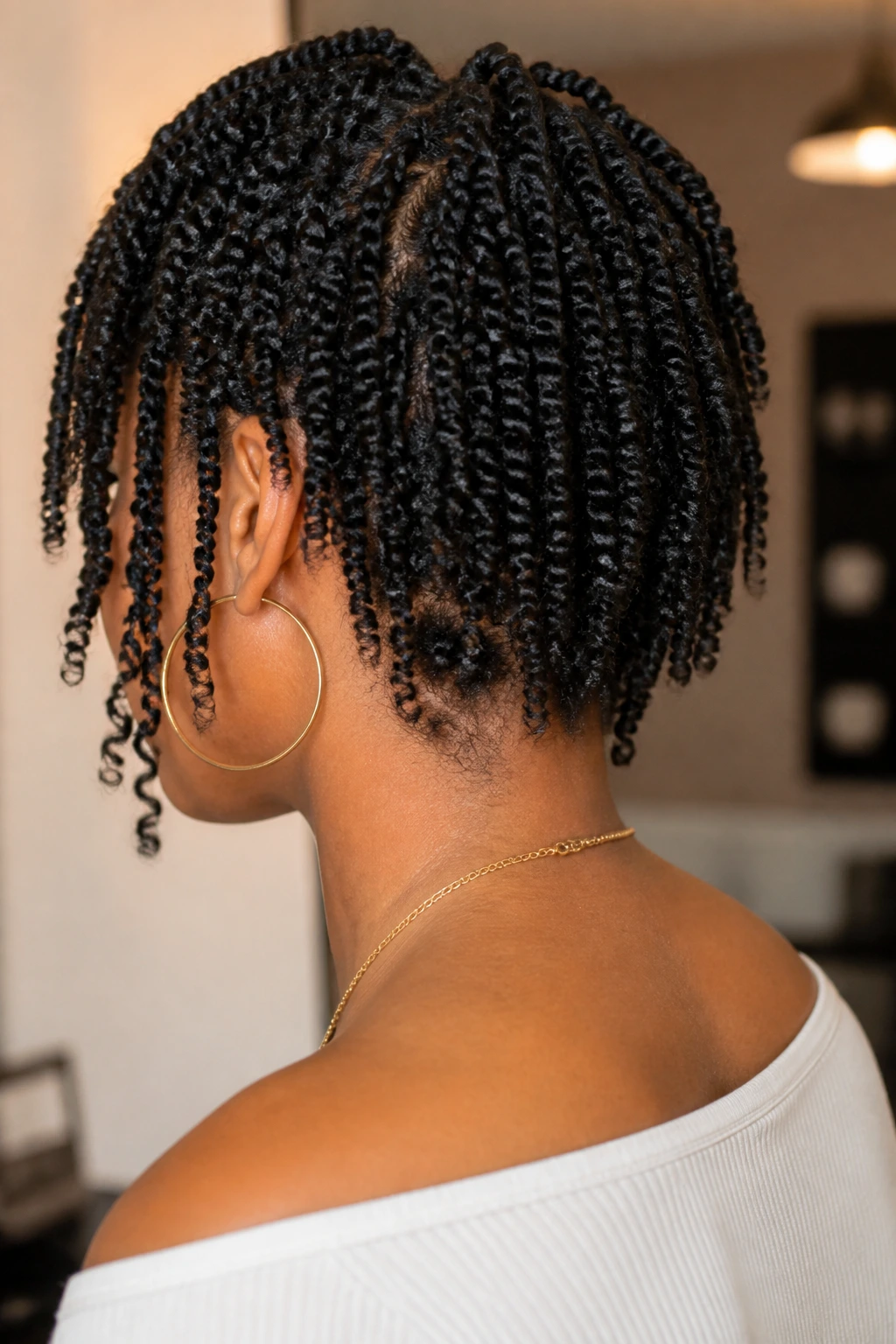 Back view of a real woman showing tapered nape-grazing twists in a salon.