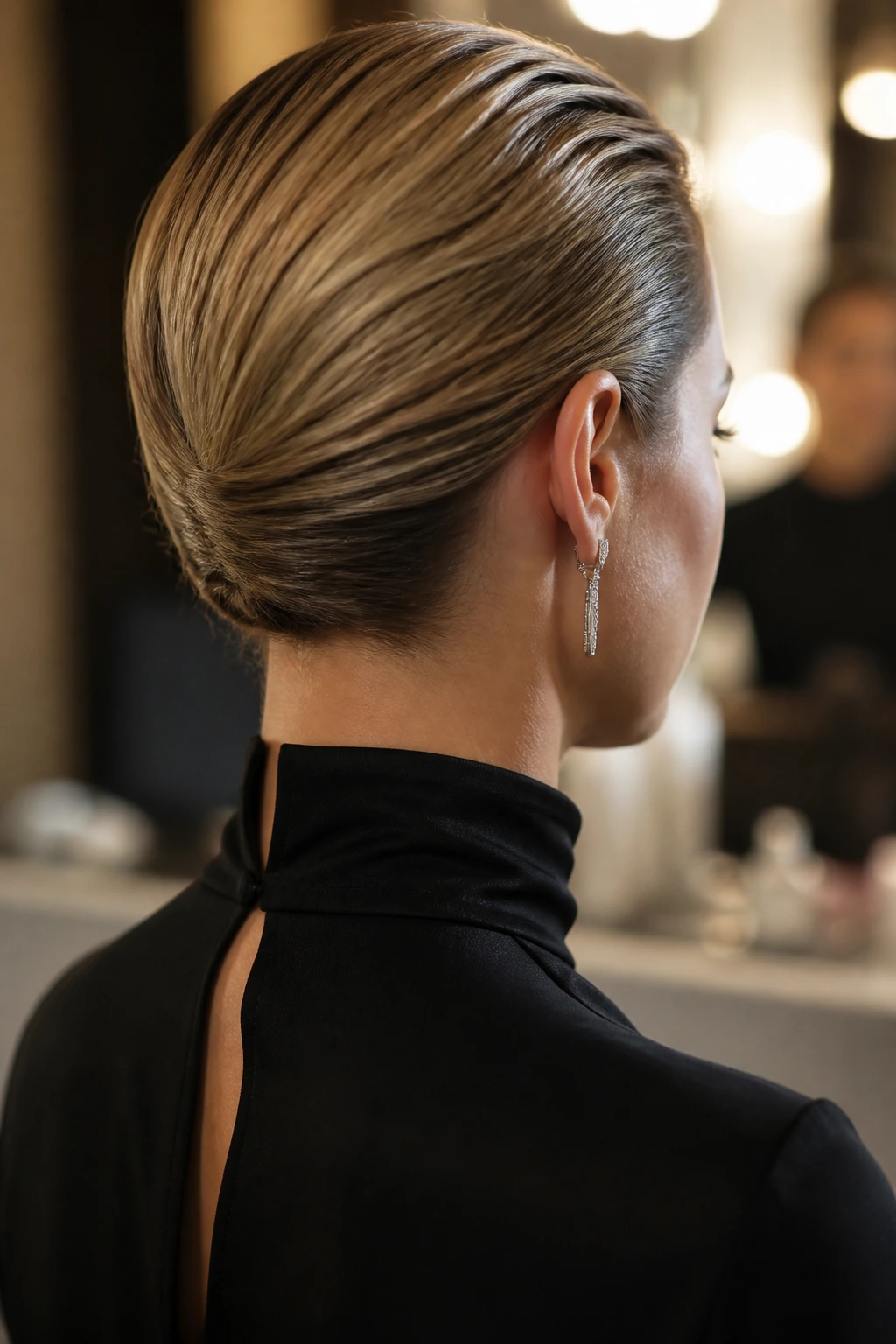 Rear portrait showing a nape-hugging tuck with hair pinned low at the back
