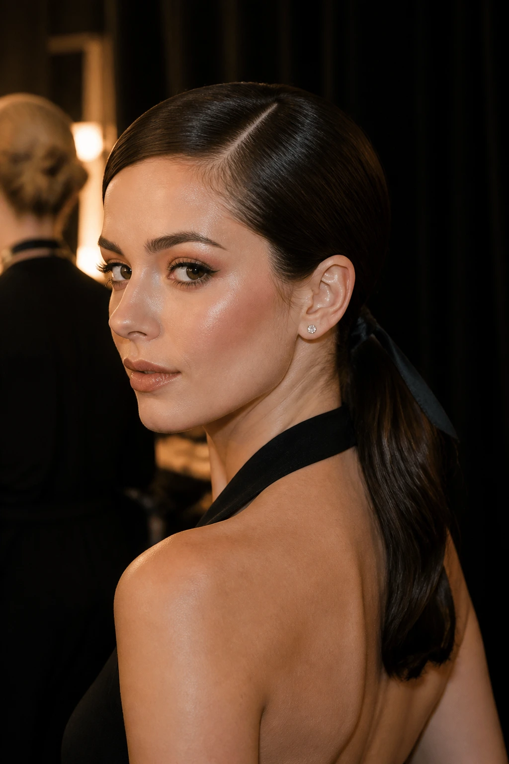 Close-up of a real woman with a sleek Modern Noir Low Ponytail for bridal styling, moody lighting.