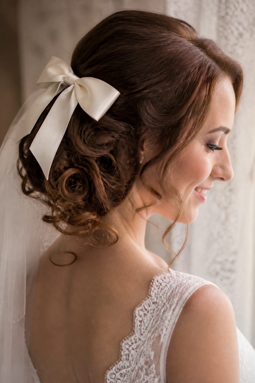 Close-up of a bride with pinned ringlets and a satin bow