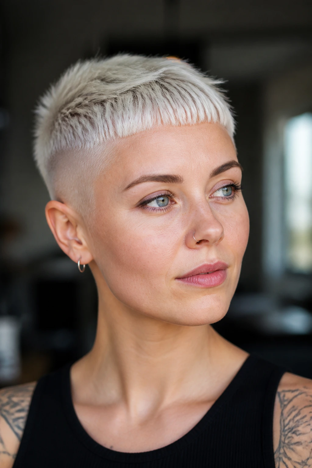 Close-up portrait of a real person with platinum micro-fringe undercut pixie in cool daylight.