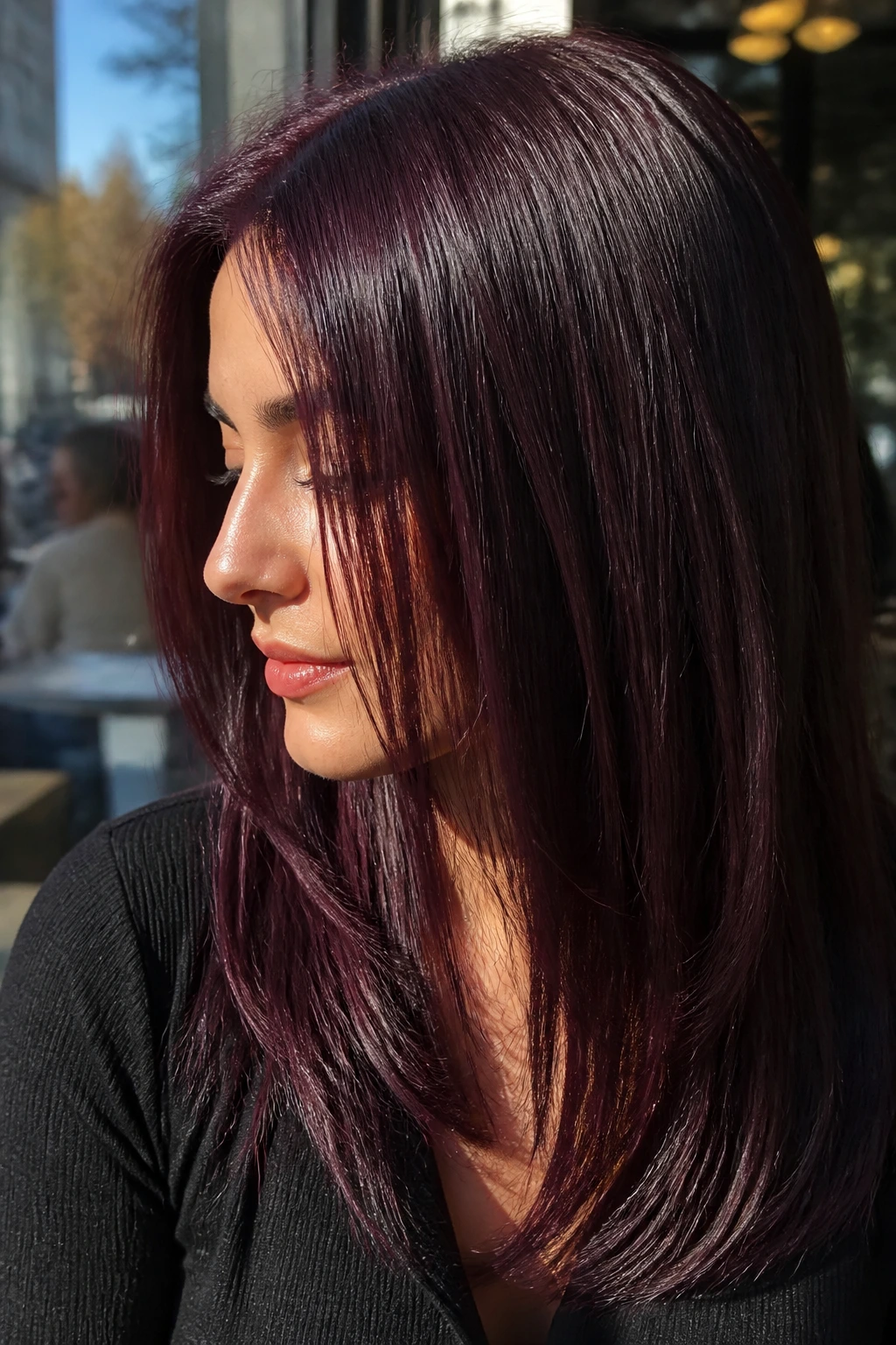 Close-up of a real woman with plum-black shine on straight hair in bright natural light