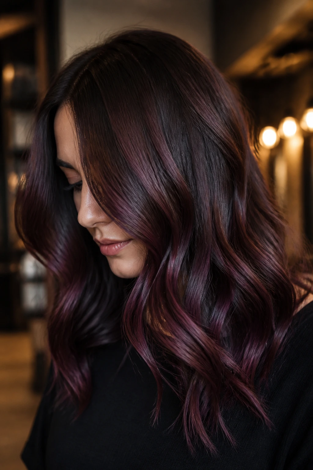 Close-up portrait of a real woman with plum brown balayage showing violet-brown sheen.