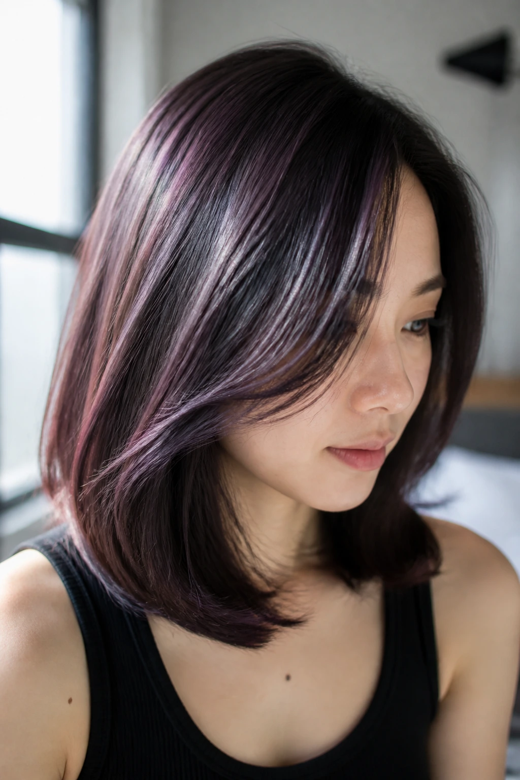 Close-up of dark hair with plum brown highlights catching sunlight.