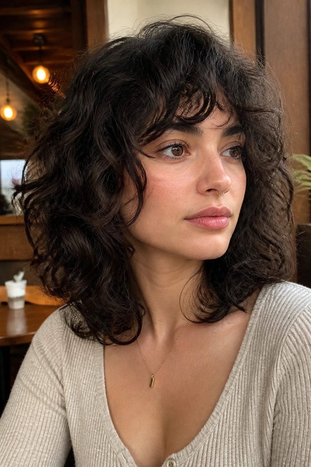 Close-up portrait real woman rounded collarbone wolf cut in cafe lighting
