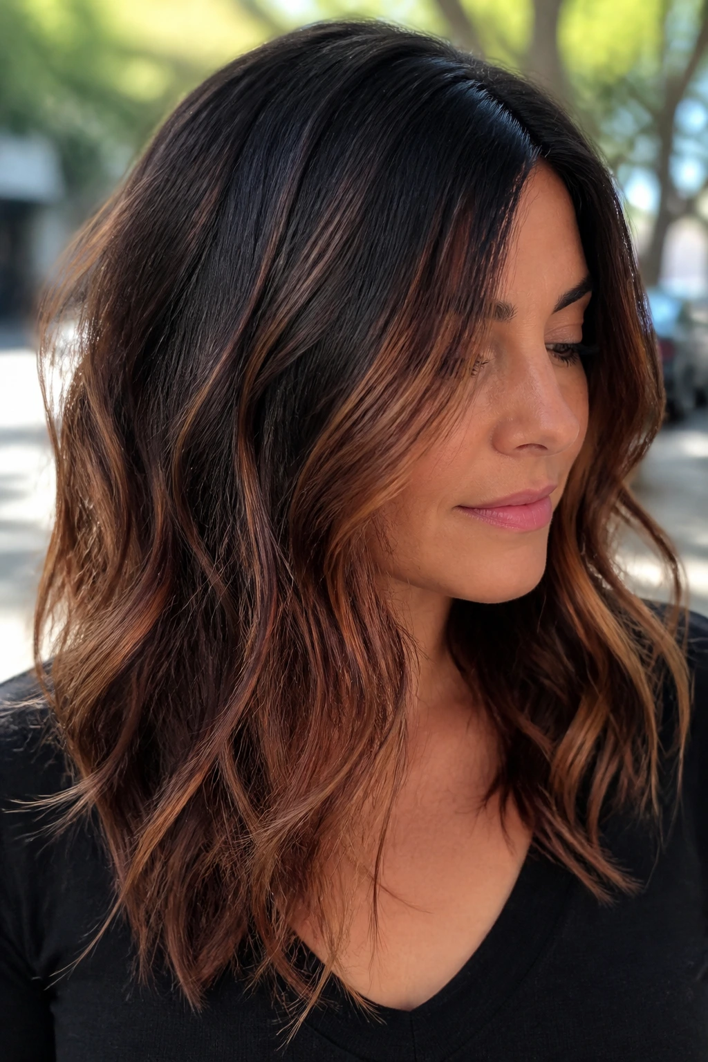 Portrait of a person showing rustic copper balayage on brunette hair in natural light.