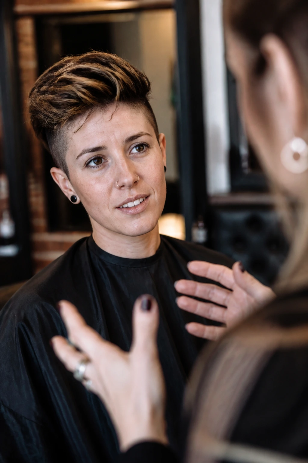 Portrait of client in a salon chair discussing haircut details with a stylist