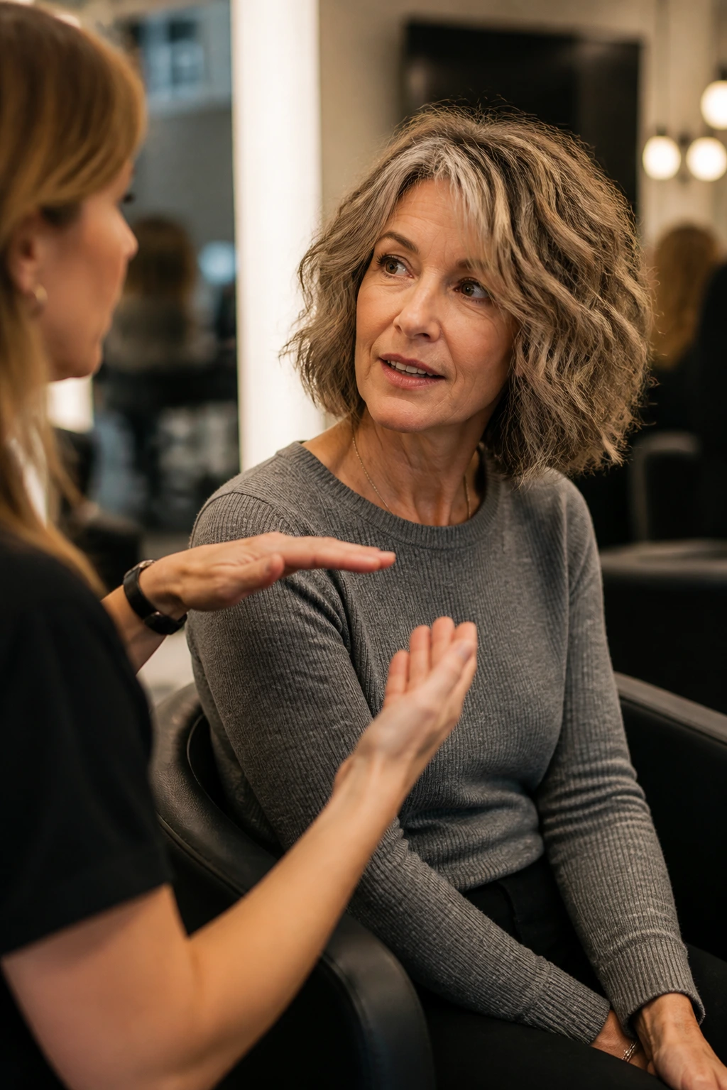 Real client and stylist in a salon discussing haircut in a candid side-profile moment
