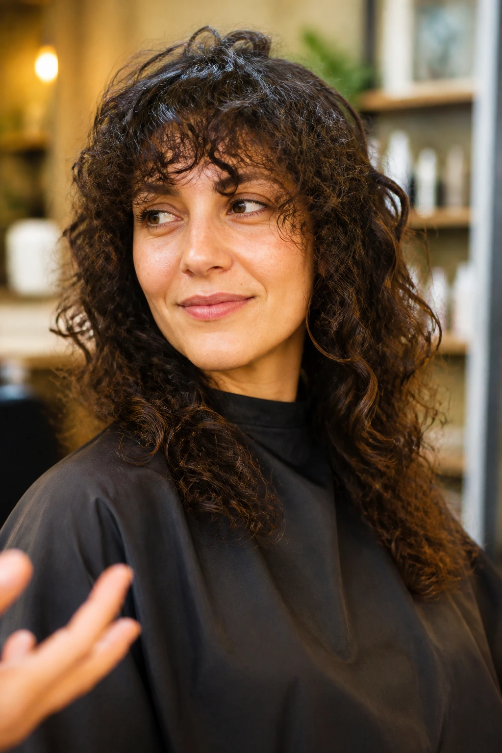 Close-up portrait of a real woman in a salon chair discussing a curly cut.