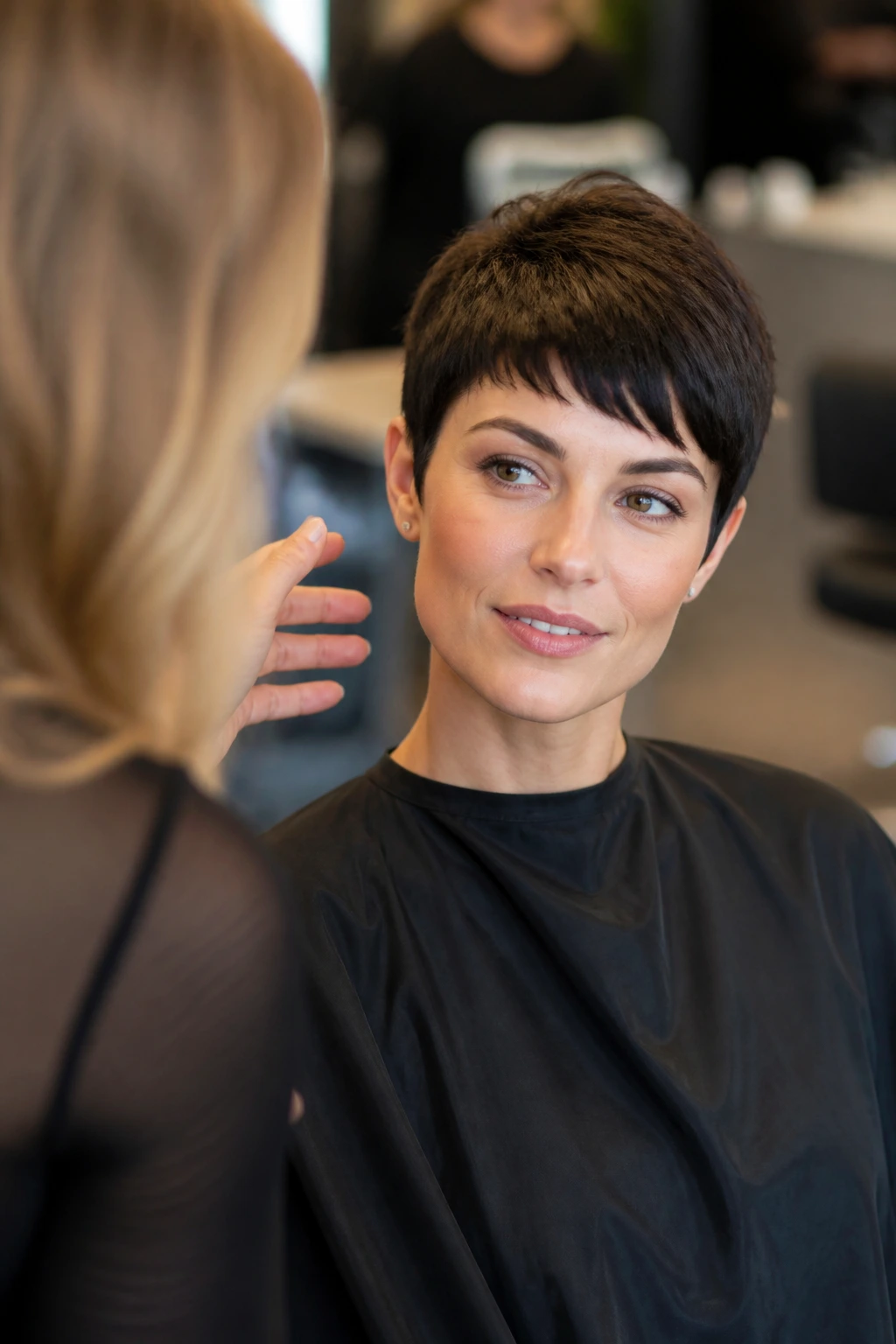 Close-up of a real client in a salon discussing pixie cut details with a stylist