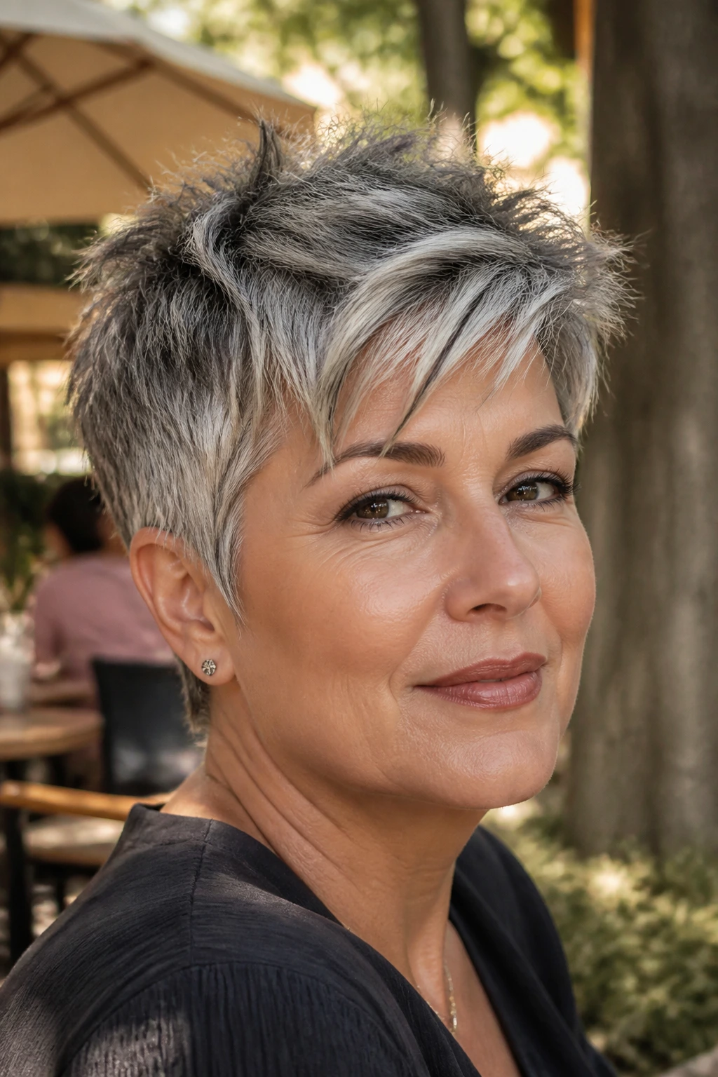 Close-up portrait of a real woman with a tousled salt-and-pepper pixie.