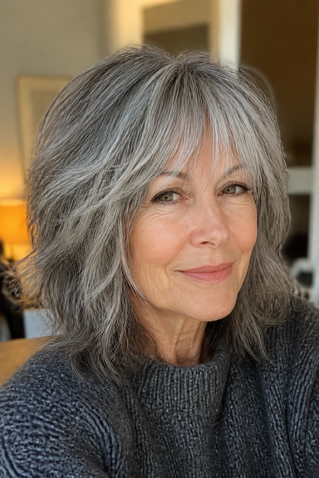 Real woman with salt-and-pepper soft shag hairstyle in a cozy home