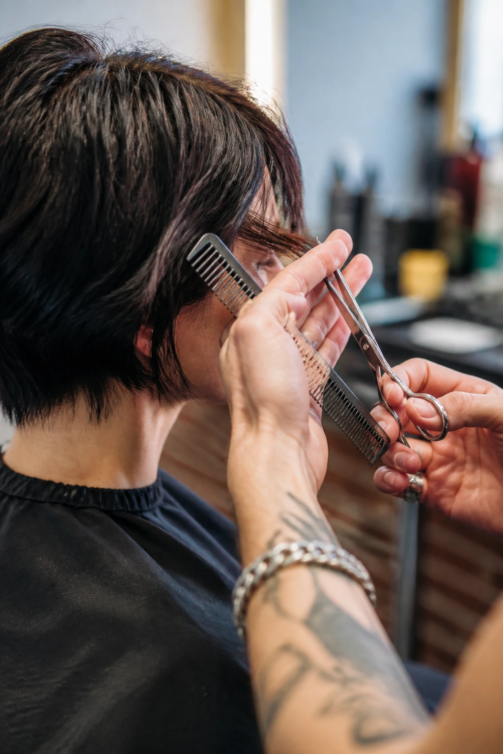 Close-up of stylist hands using scissors and comb in a salon.