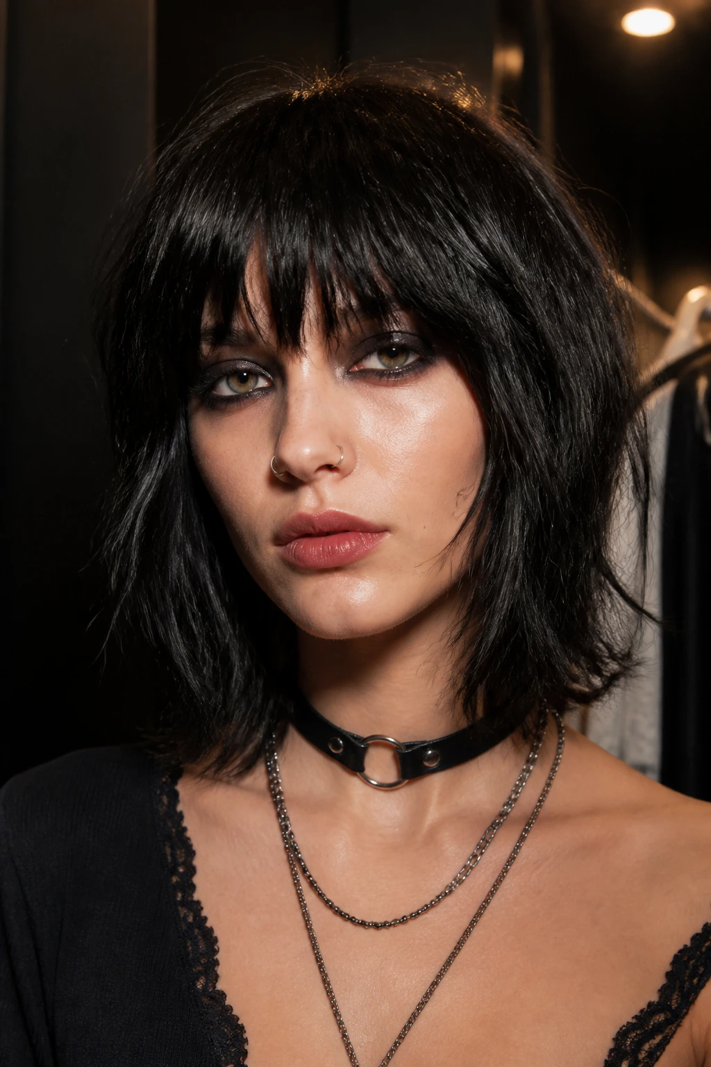 Close-up of a real woman with shaggy lob and eye-skimming fringe in moody backstage lighting