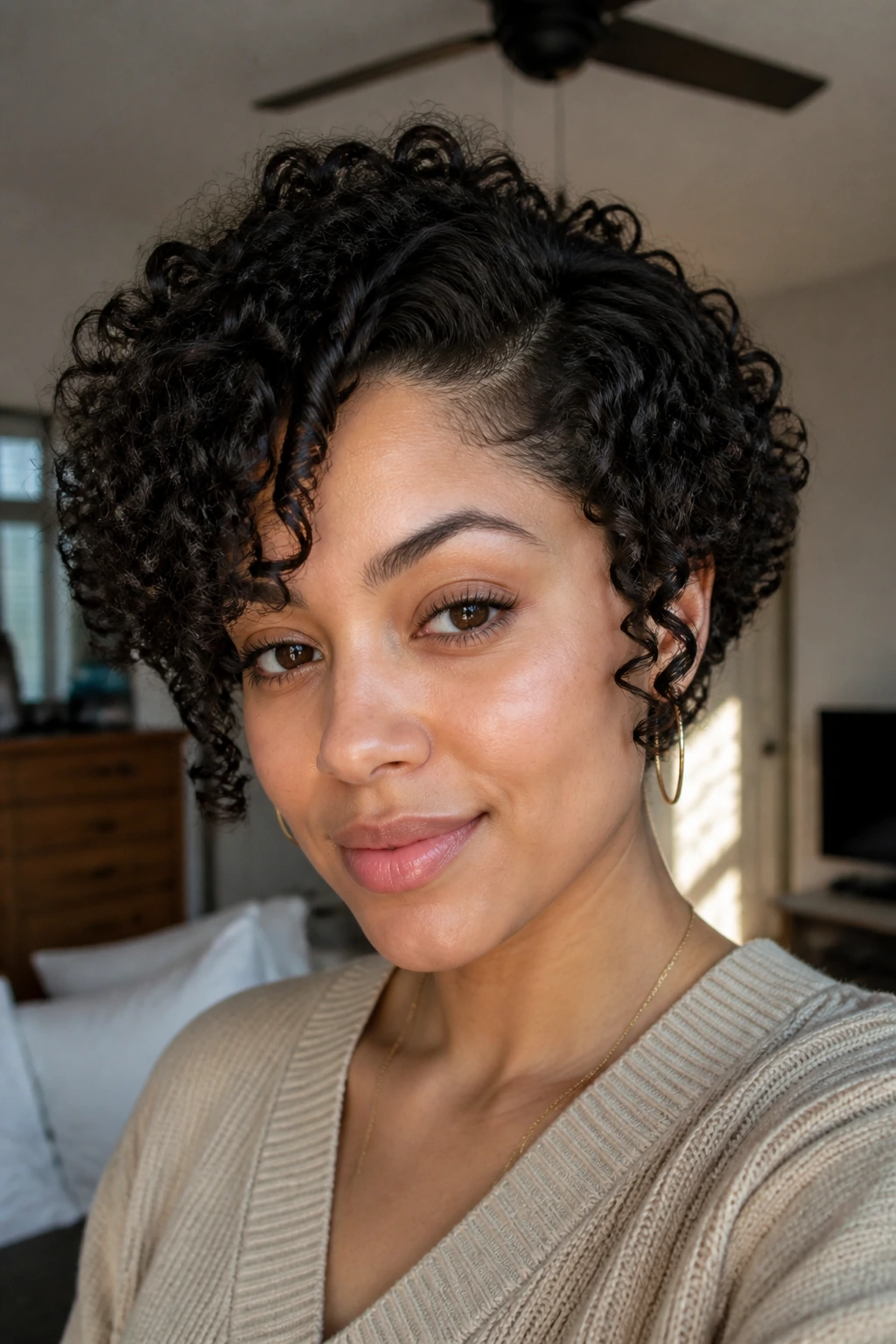 Close-up portrait of a real woman with short 2C curls and crown height on a round face, side window light.