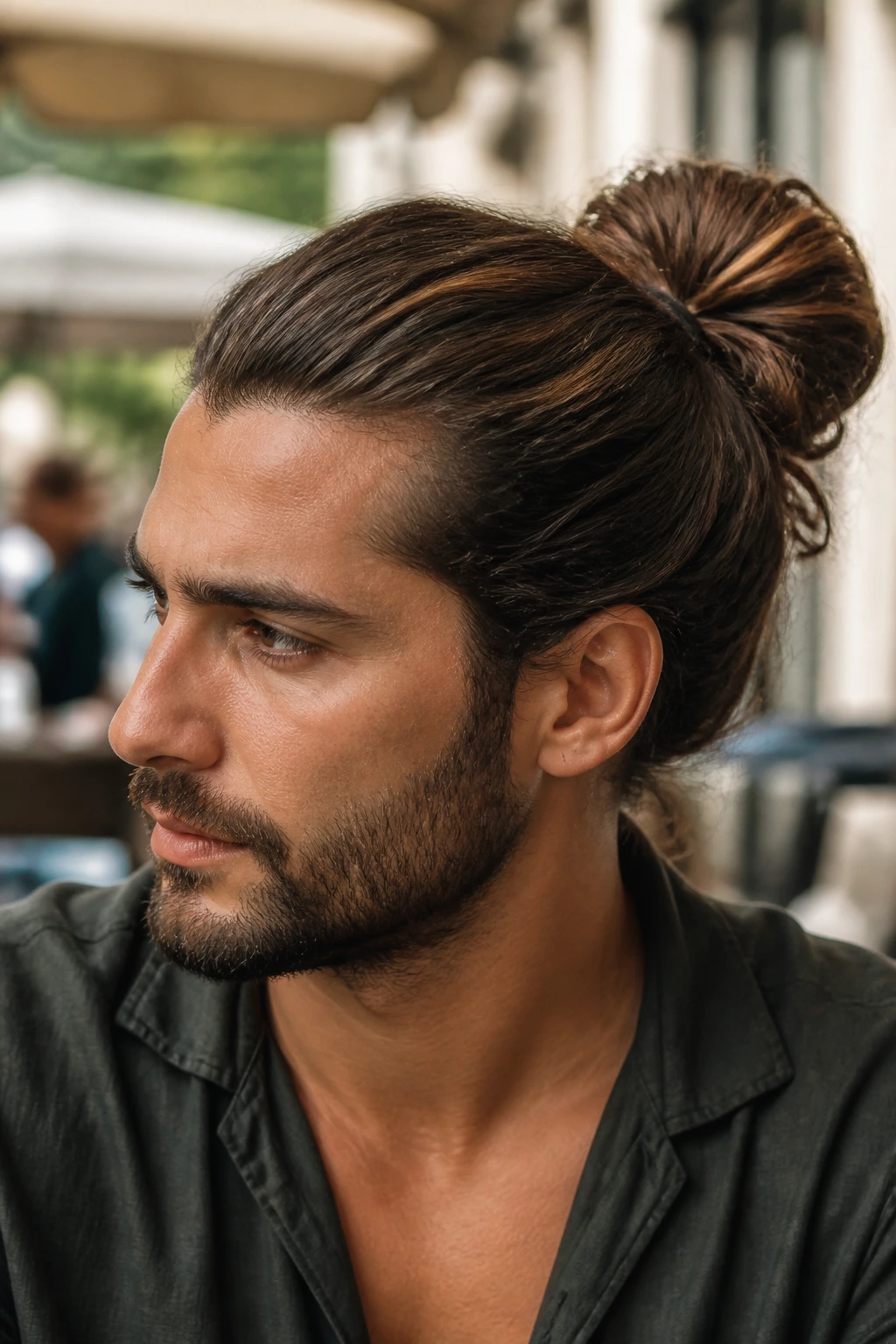Man with shoulder-length hair in a full bun outdoors
