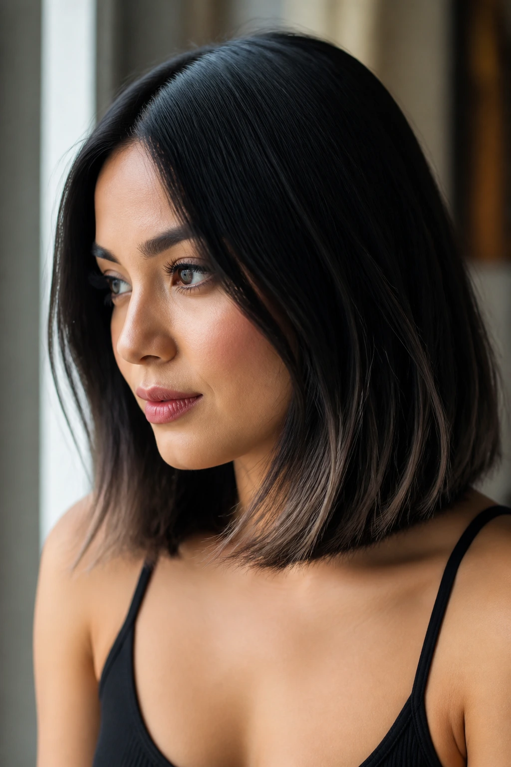Close-up of a real woman with shoulder-length hair transitioning from black to smoky ash brown ends under window light