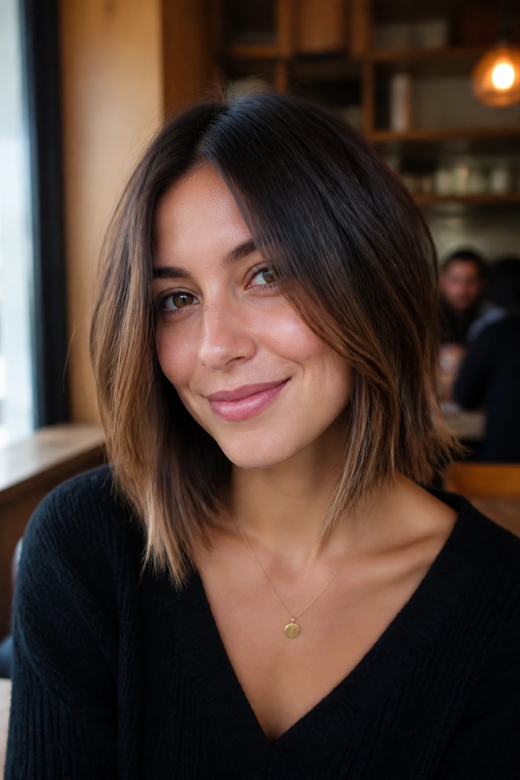 Close-up portrait of a real person with a soft A-line lob under cafe lighting