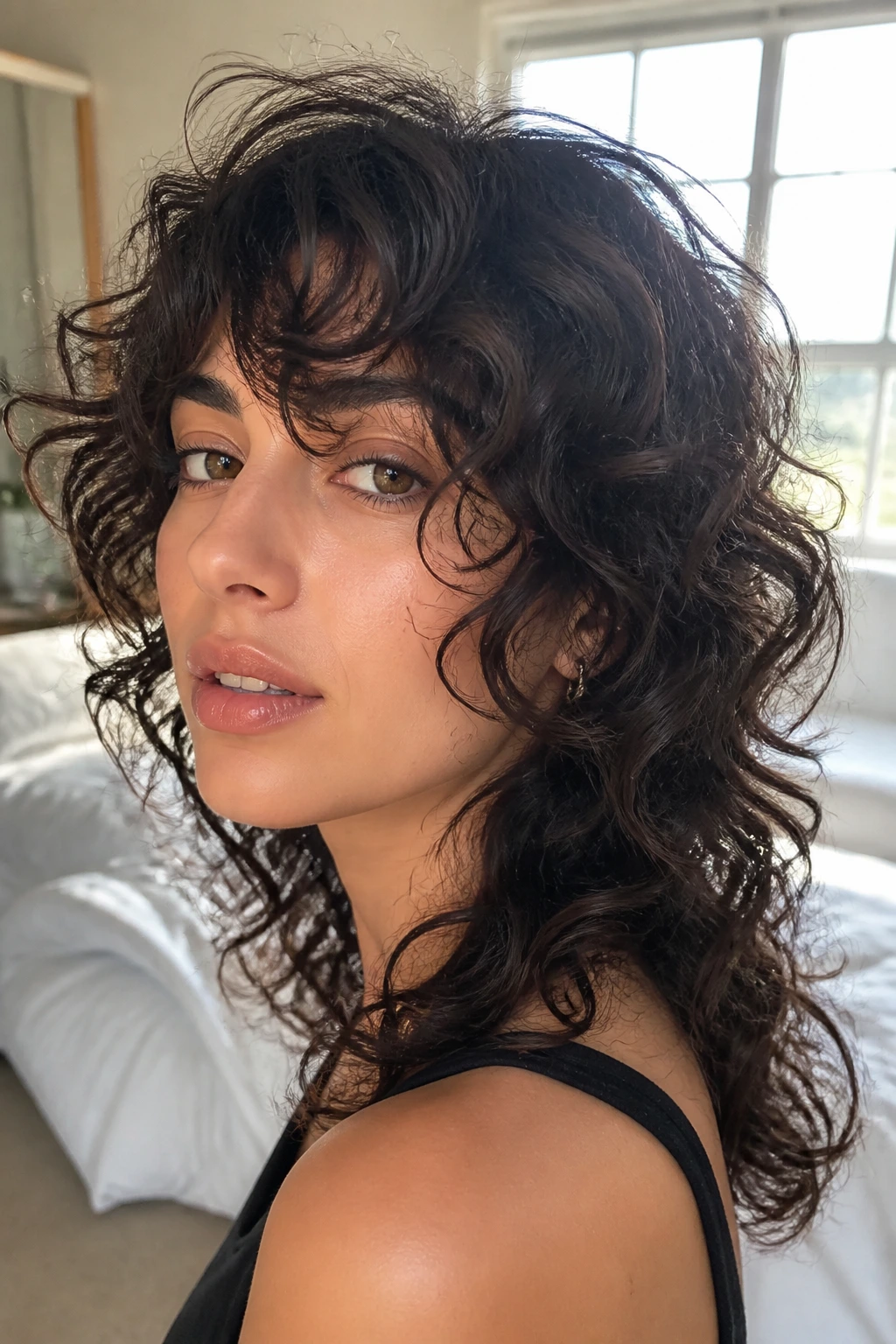 Close-up portrait of a real person with soft face-framing curly shag showing cheekbone framing