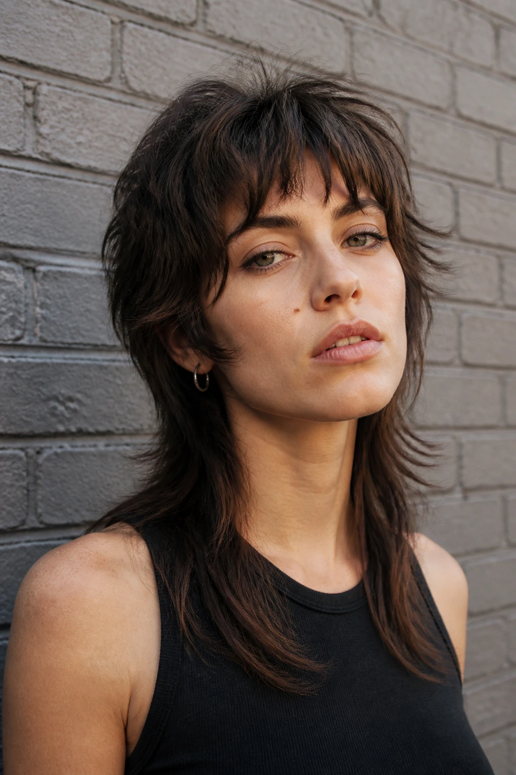Portrait of a real person with a soft wolf mullet against a brick wall outdoors