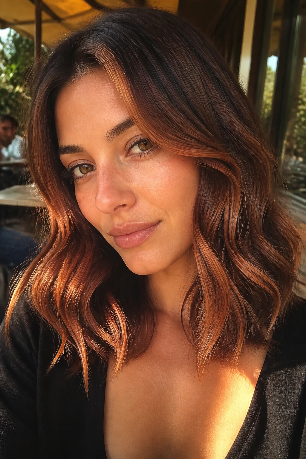 Close-up of a real woman's wavy hair with strawberry brunette pieces in a sunlit setting