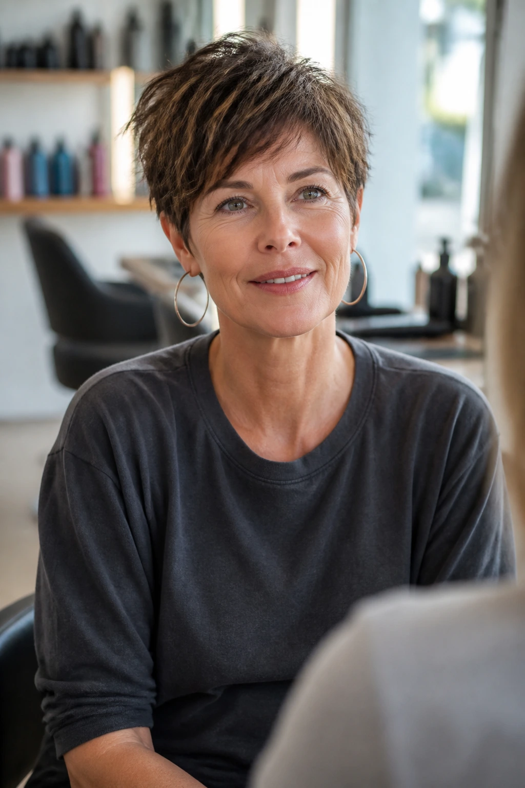 Portrait of a woman in a salon chair ready to discuss her pixie cut