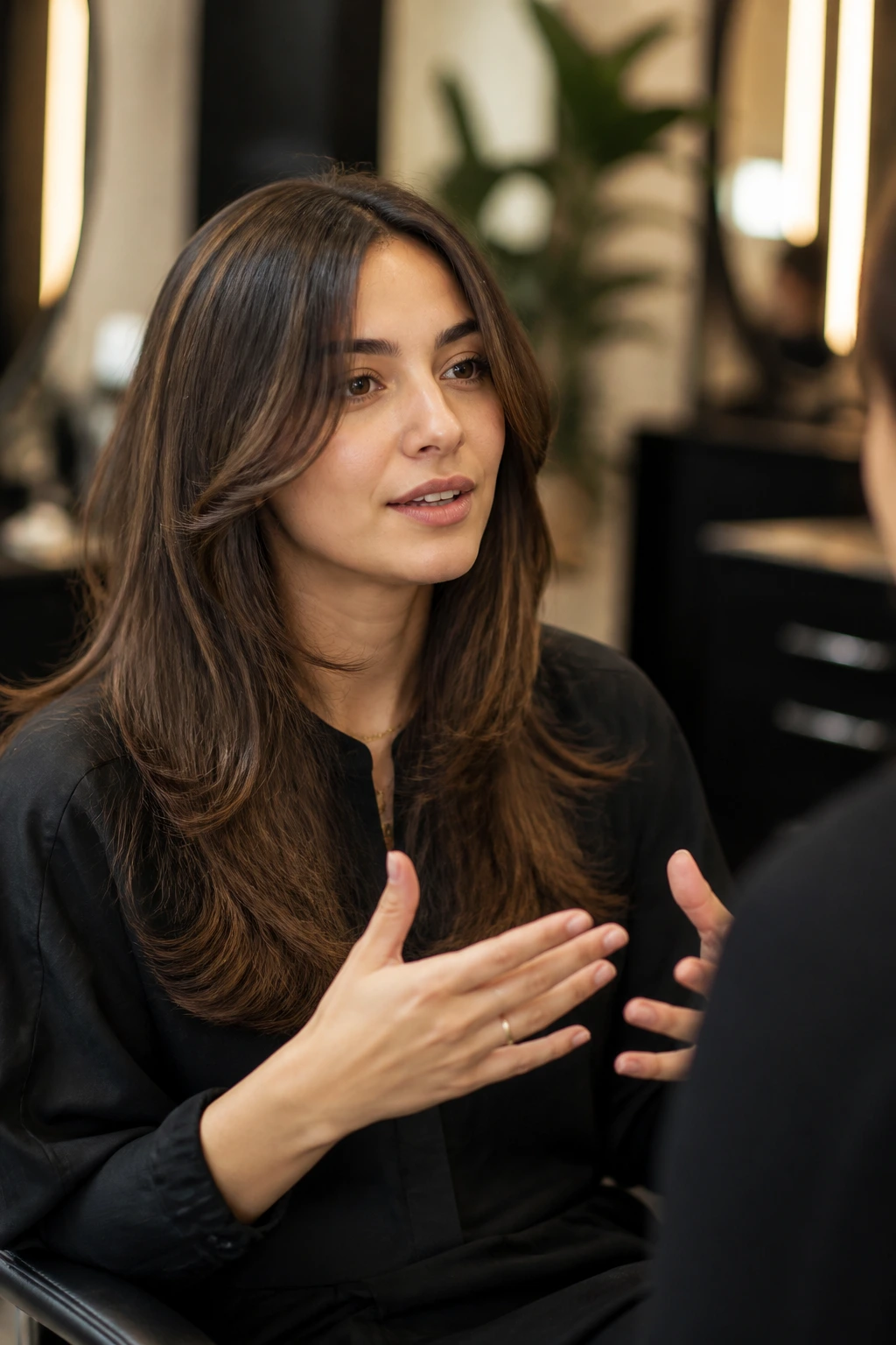 Close-up of client in salon chair discussing preferences before a snip