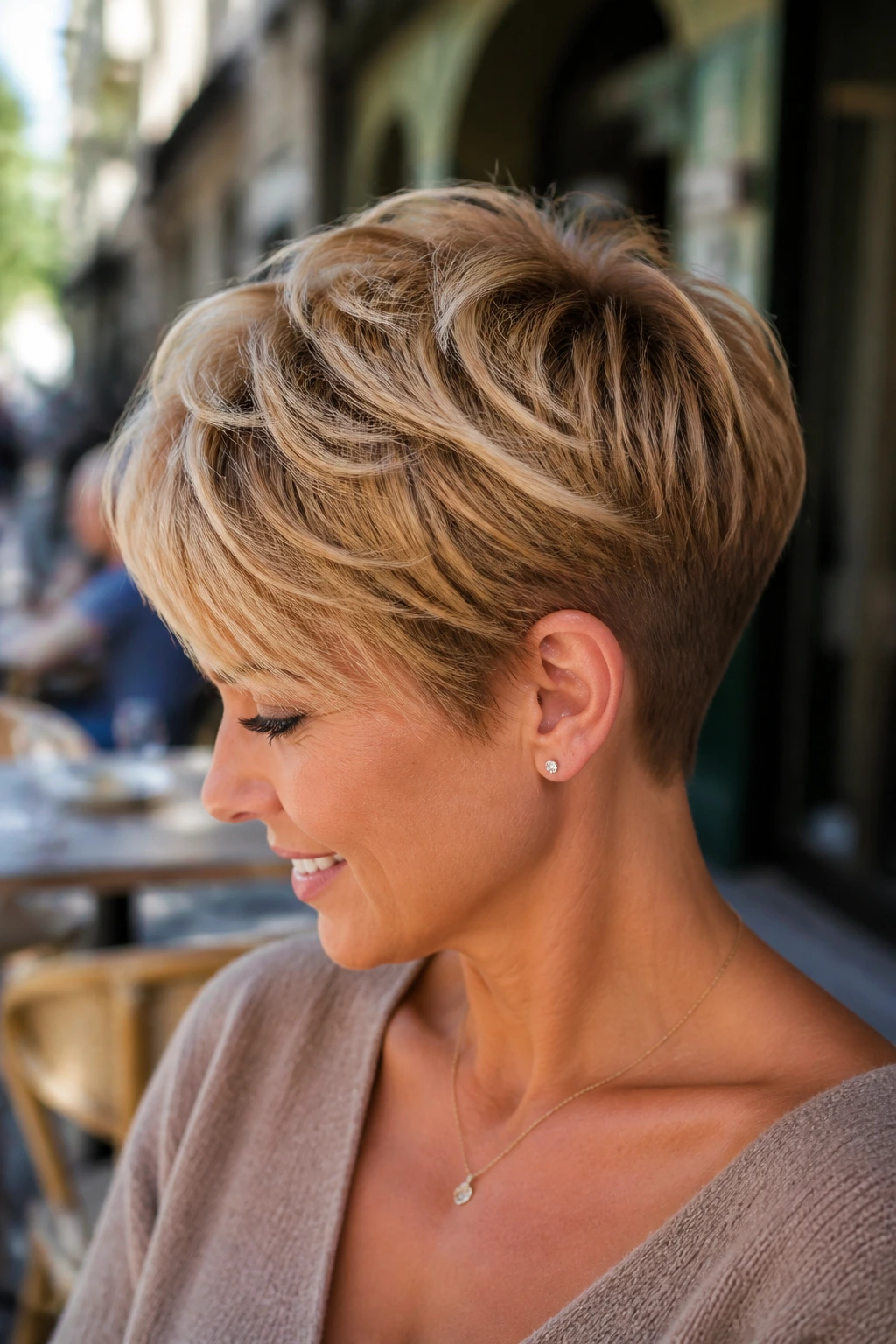 Close-up of a real woman with a tapered nape pixie in sunlit outdoor cafe