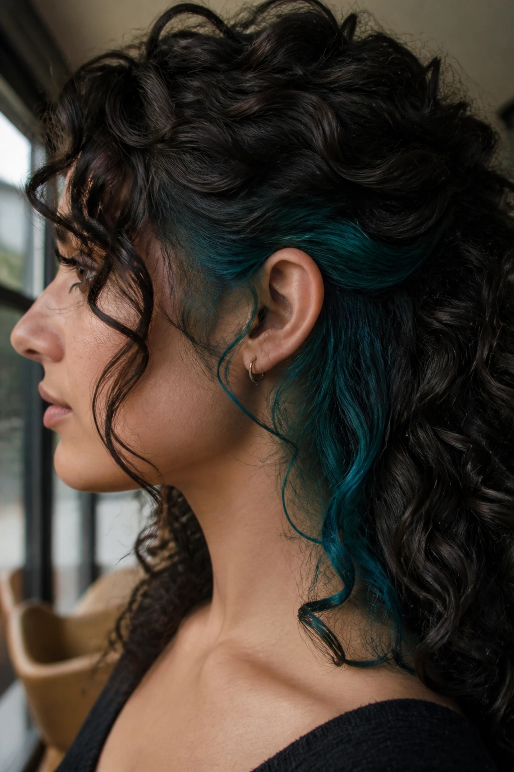 Curly hair with teal underlayer peeking through on a real person
