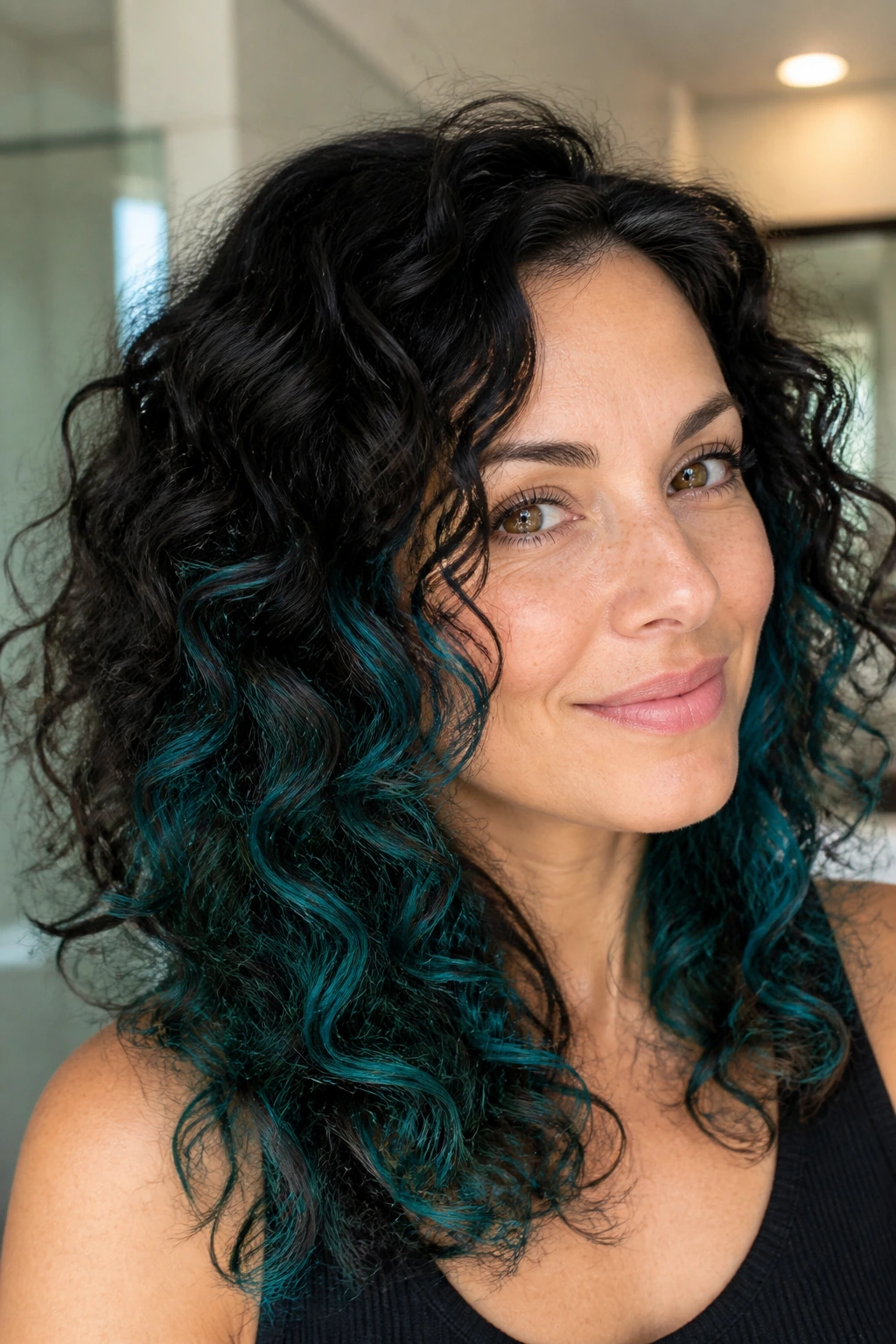 Close-up of teal underlights peeking through curls on a real woman