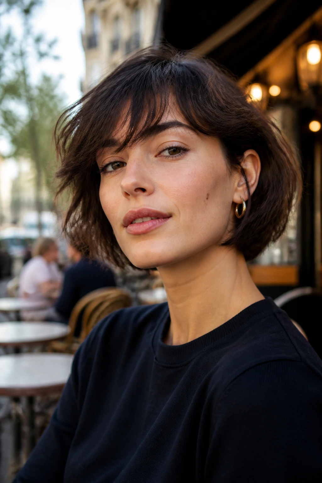Close-up of a woman with a textured French bob and soft fringe in urban daylight