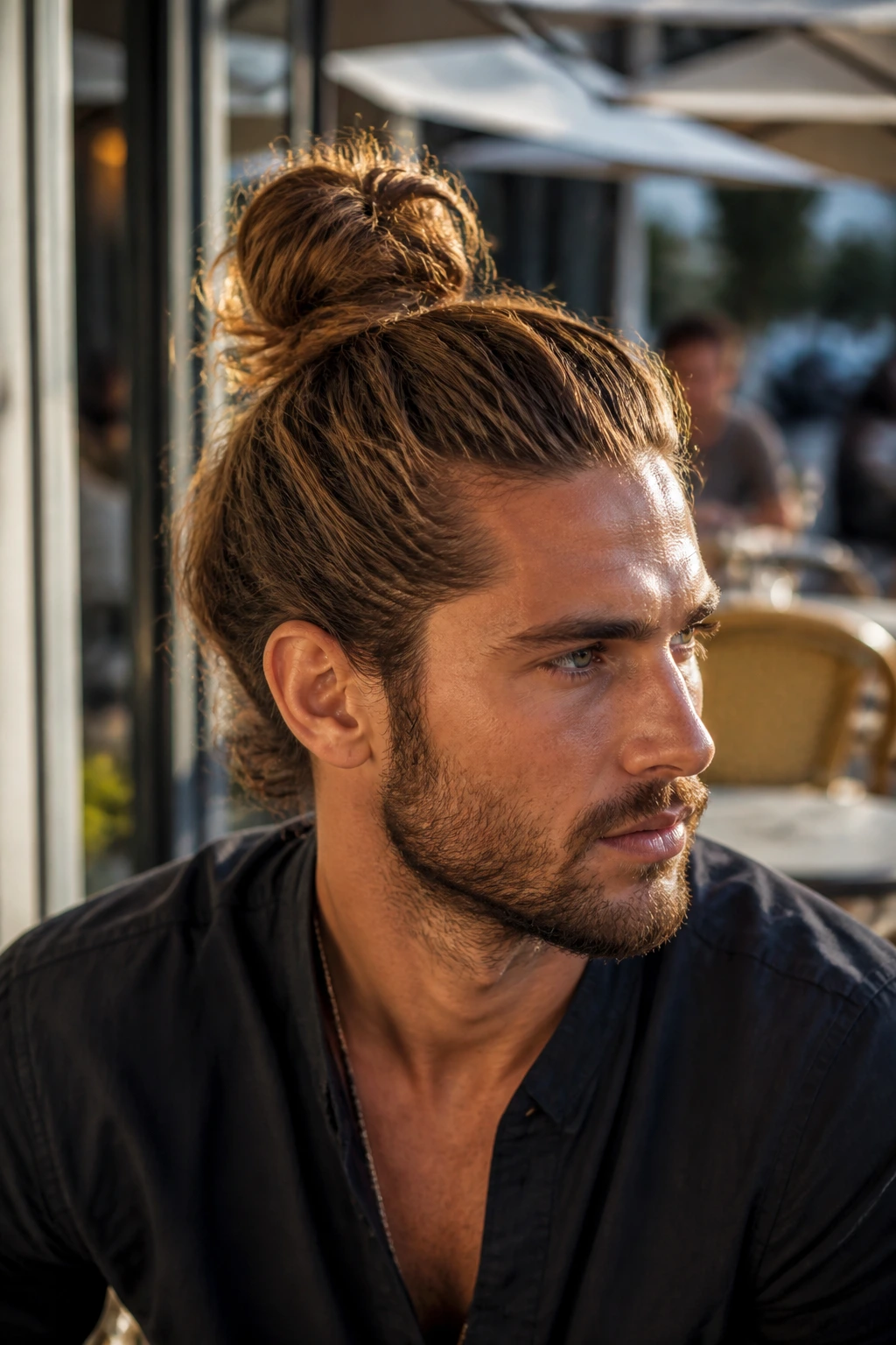 Close-up portrait of a man with a textured top knot in outdoor light
