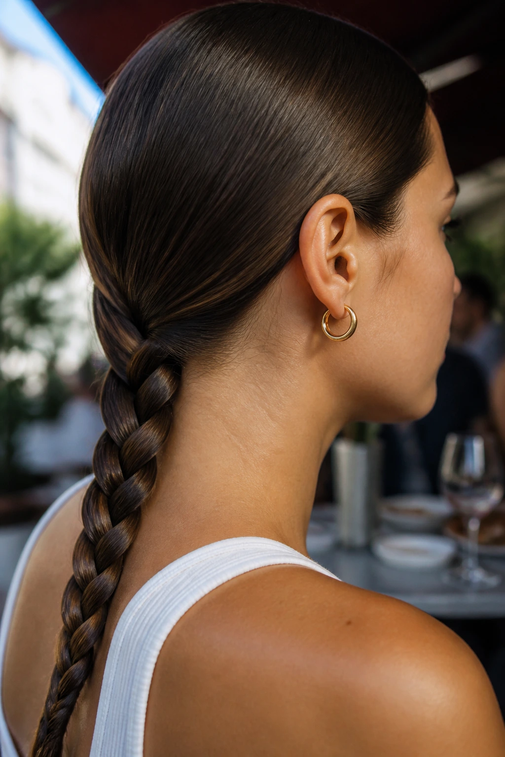 Real person with sleek low three-strand braid at the nape