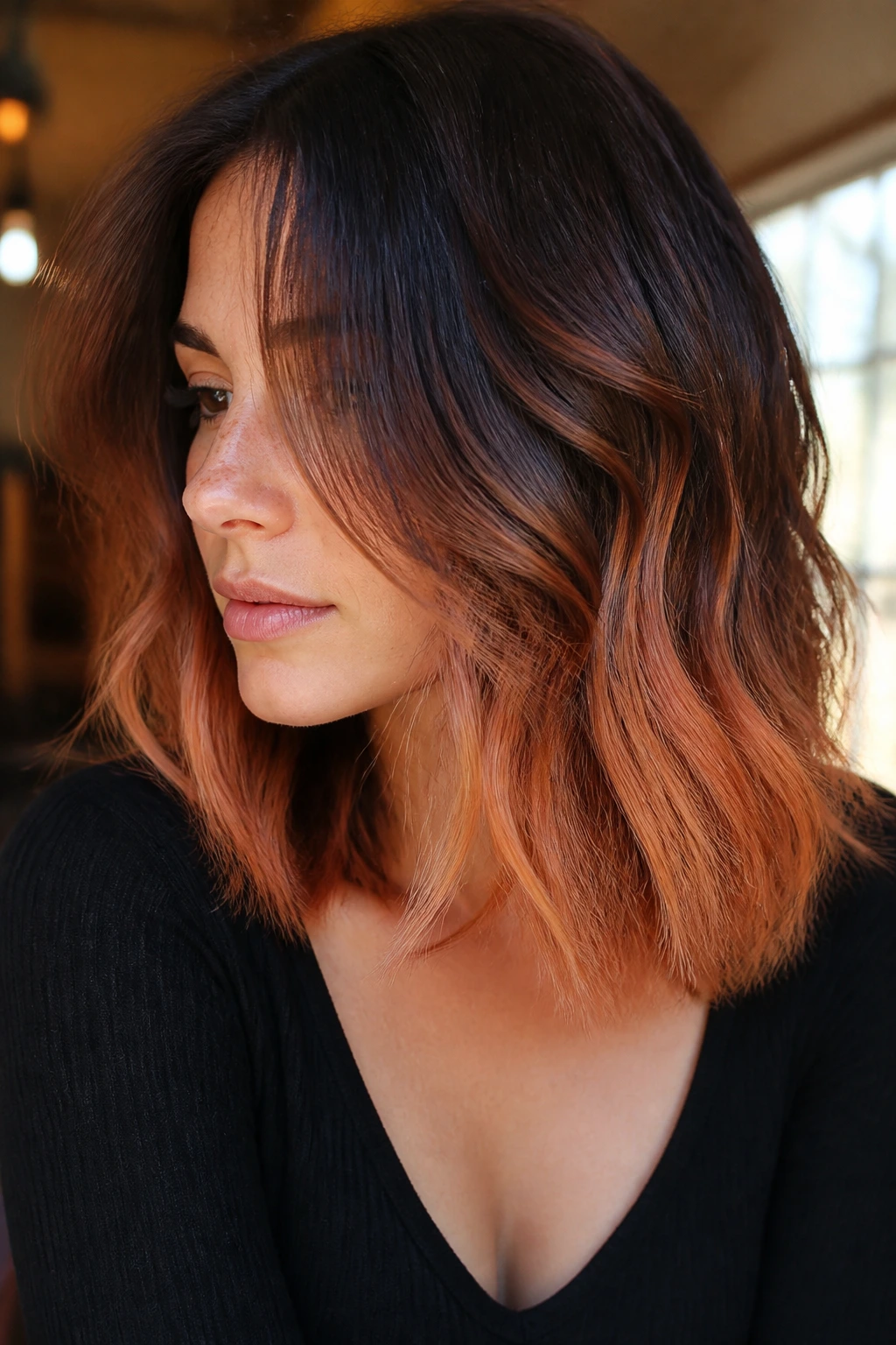 Close-up of a real woman's hair ends dyed toasted apricot color against a darker base.
