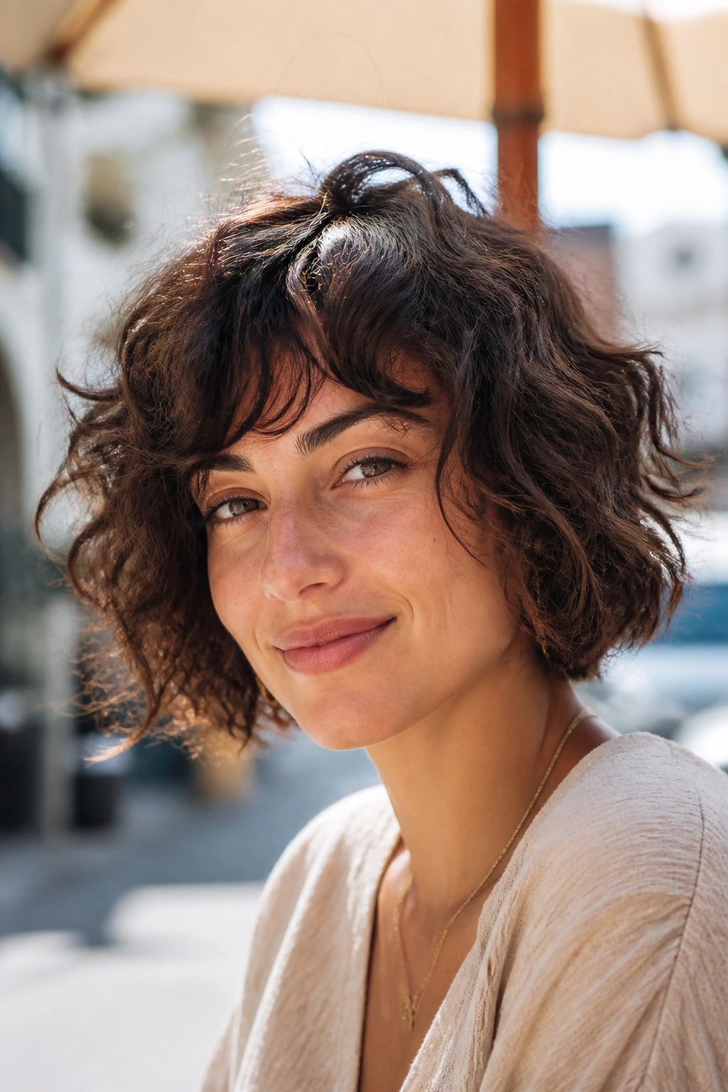 Close-up portrait of a real woman with tousled bob shag in a sunlit street scene.
