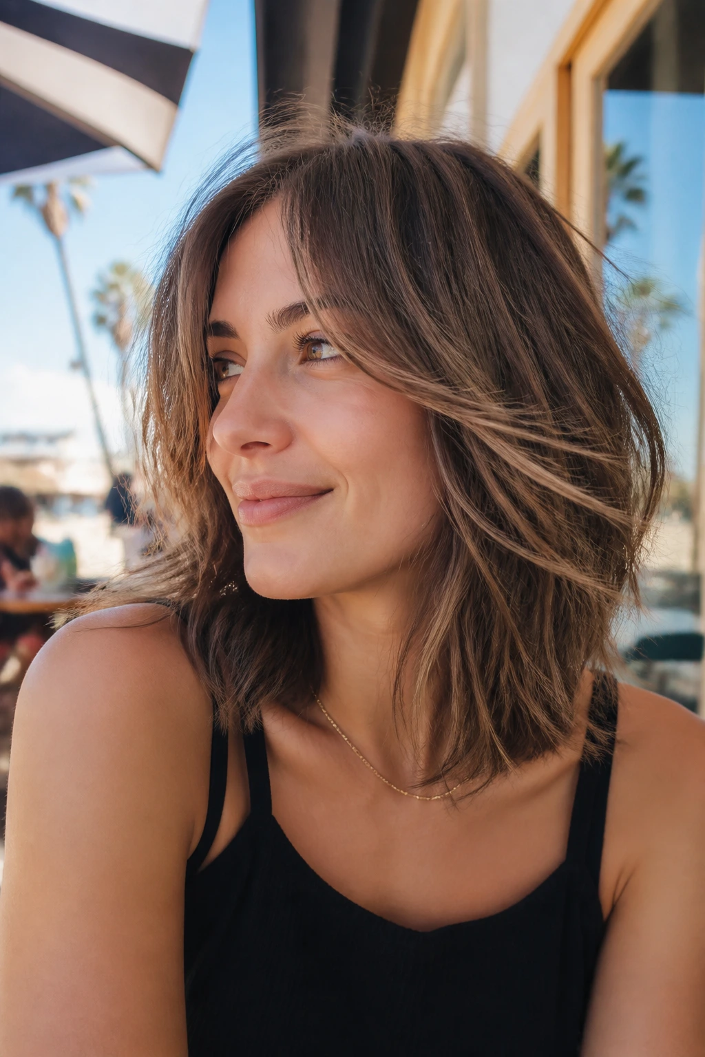 Close-up of a real person with tousled lob and long curtain fringe in outdoor sunlight